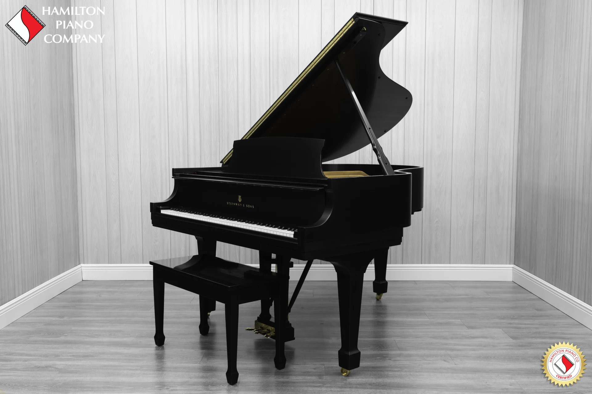 A Steinway M baby grand piano in a beautiful satin ebony finish with brass hardware and a bench.