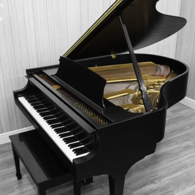 A Steinway M baby grand piano in a beautiful satin ebony finish with brass hardware and a bench. The image shows off the interior of the piano including the harp and strings.