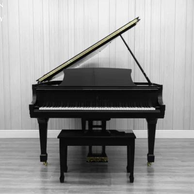 A Steinway M baby grand piano in a beautiful satin ebony finish with brass hardware and a bench.