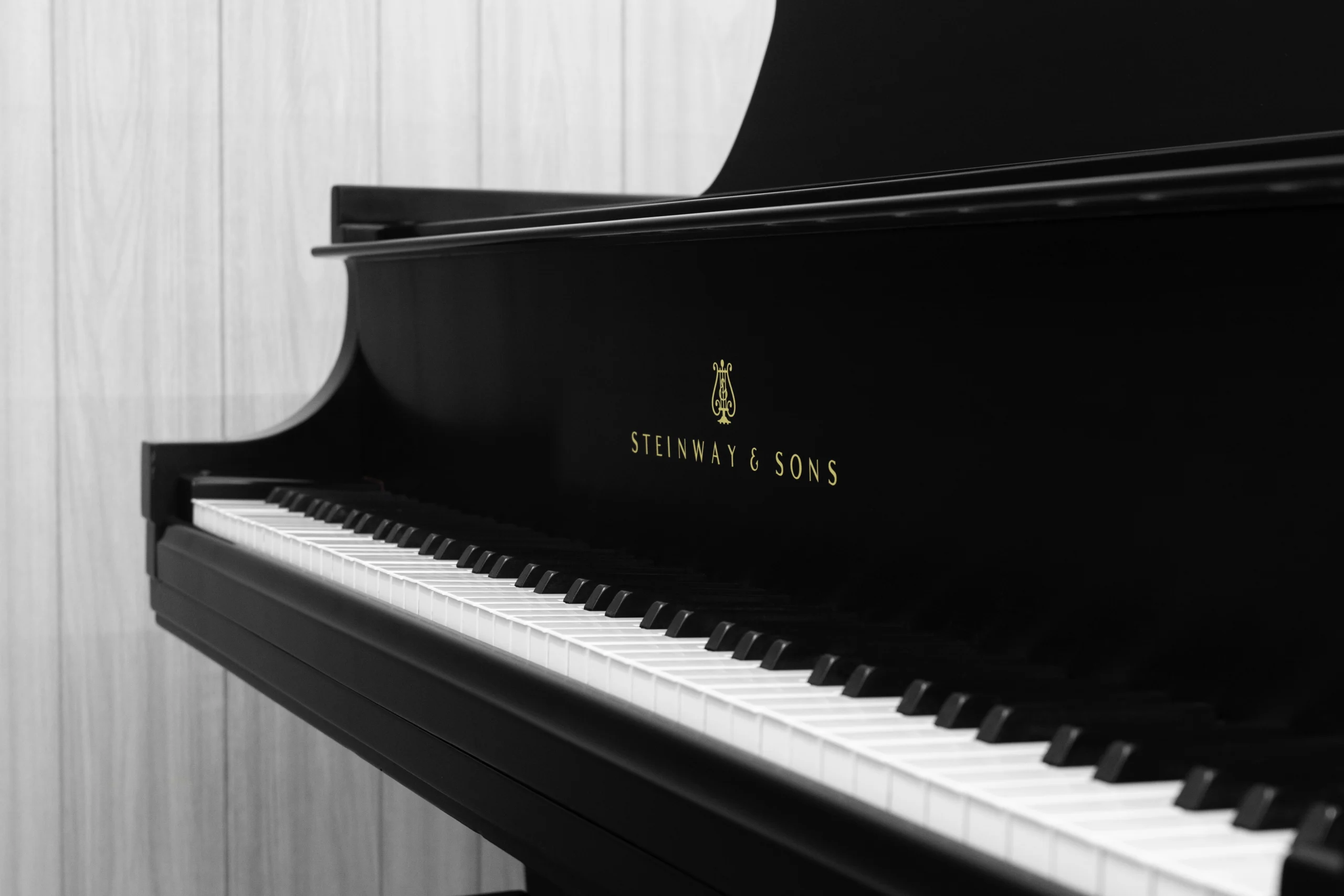 A Steinway M baby grand piano in a beautiful satin ebony finish. The image shows off the keys and Steinway logo.