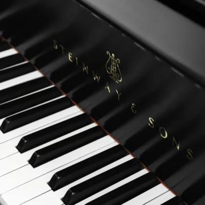 A Steinway M baby grand piano in a beautiful satin ebony finish. The image shows off the keys and Steinway logo.