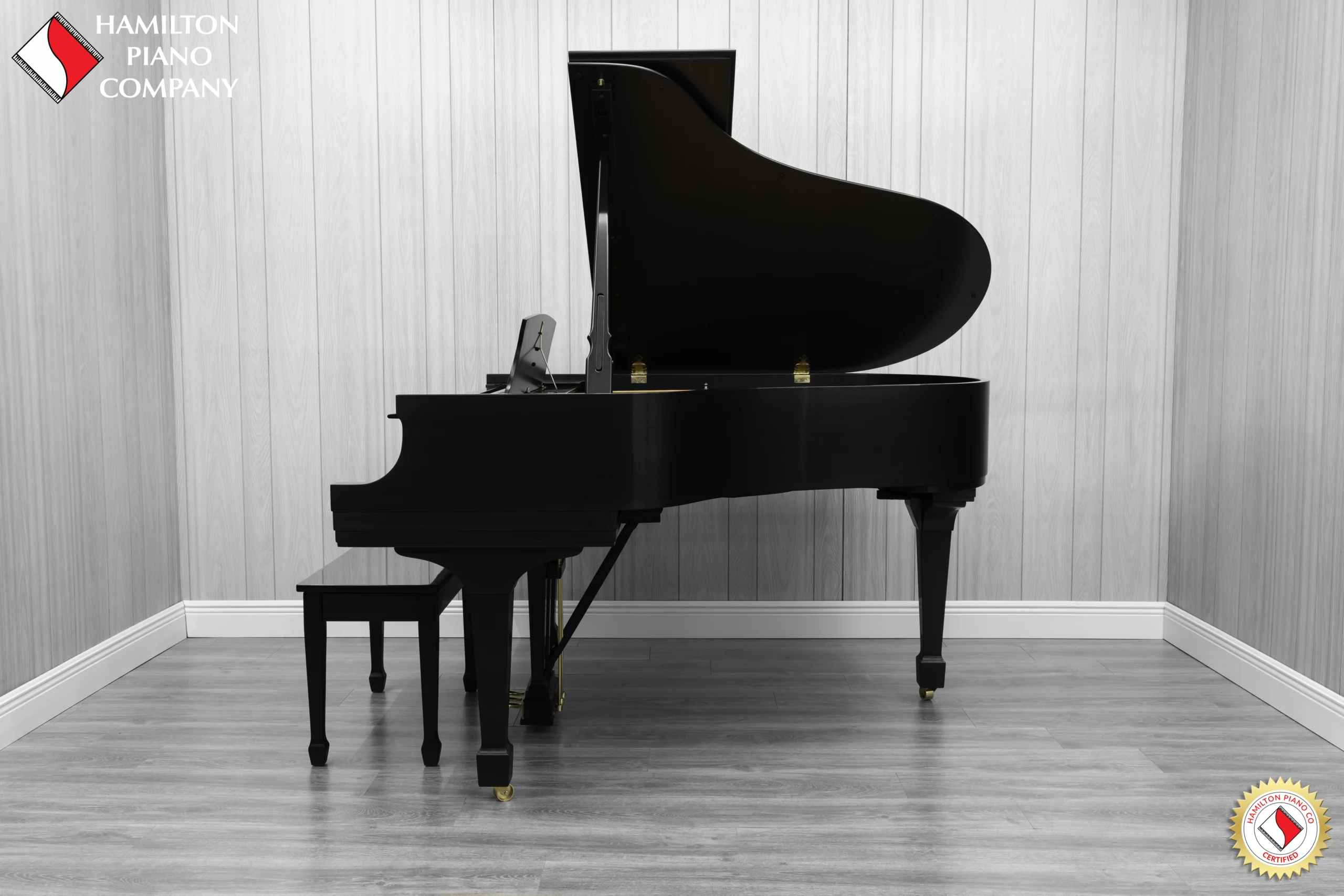 A Steinway M baby grand piano in a beautiful satin ebony finish with brass hardware and a bench.