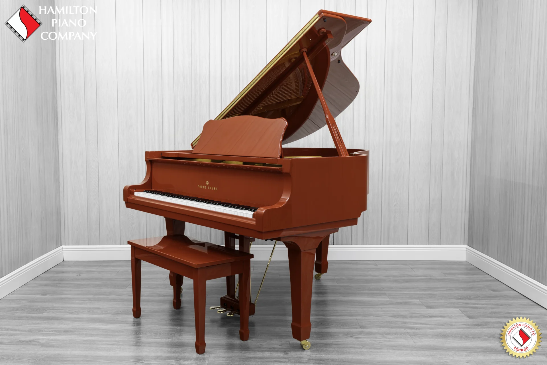 A Young Chang G-157 baby grand piano in a high polish red finish with matching bench.