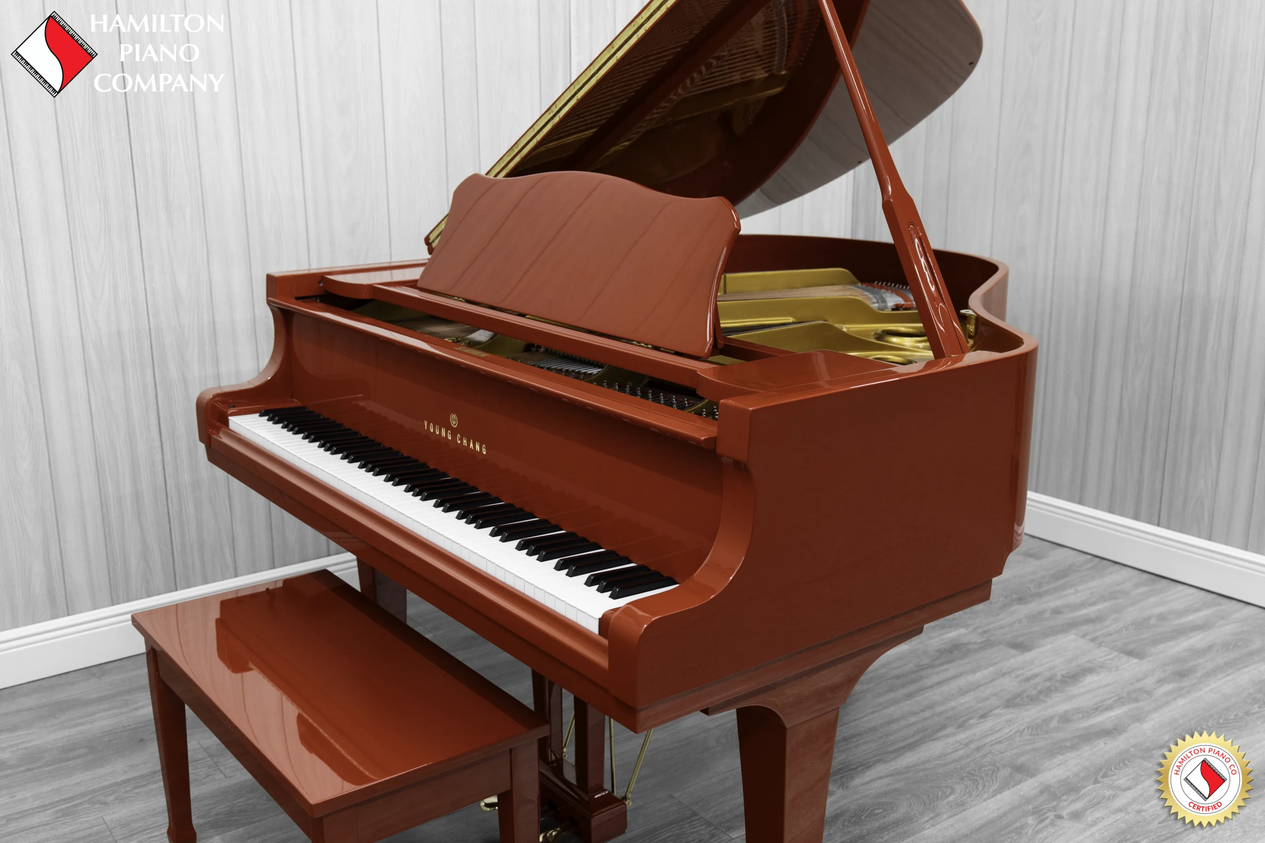 A Young Chang G-157 baby grand piano in a high polish red finish with matching bench.