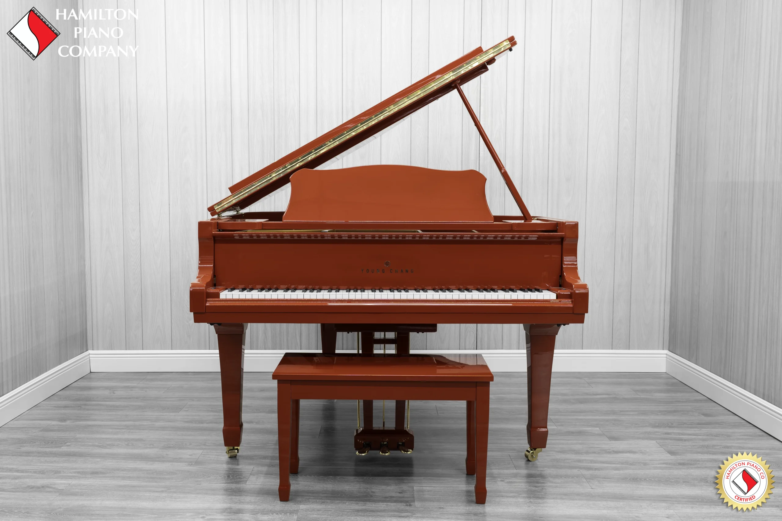 A Young Chang G-157 baby grand piano in a high polish red finish with matching bench.