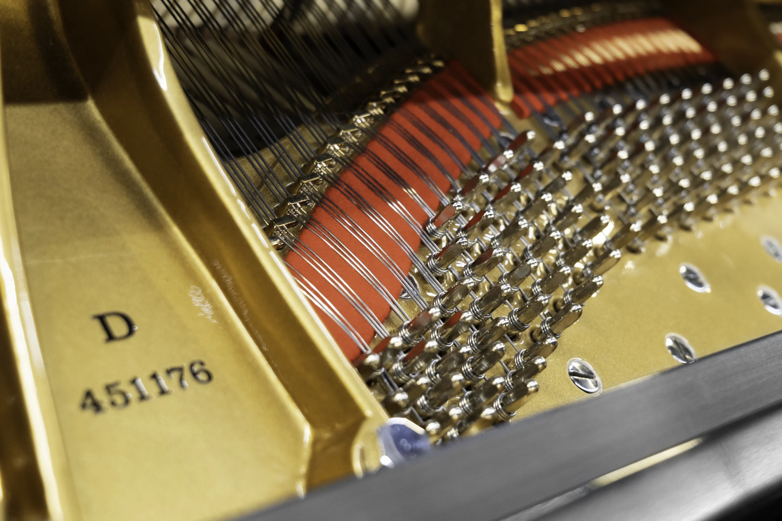 The interior of a Steinway D concert grand piano, including the harp, tuning pins, and strings.